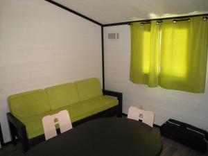 Habitación con sofá, mesa y sillas. en LES BUISSONNETS, en Saint-Georges-de-Didonne