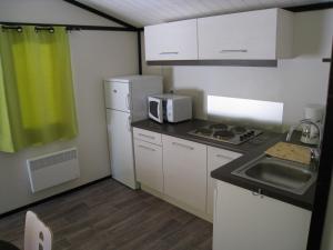 una pequeña cocina con fregadero y microondas en LES BUISSONNETS, en Saint-Georges-de-Didonne