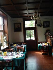 una sala da pranzo con tavoli e sedie verdi e un lampadario a braccio di Alte Kornbrennerei GBR a Poggenort