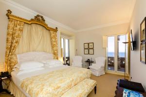 a bedroom with a large bed and two white chairs at The Albatroz Hotel in Cascais