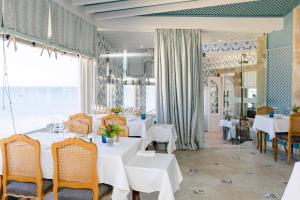a restaurant with white tables and chairs and a large window at The Albatroz Hotel in Cascais
