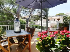 a patio with a table and an umbrella and flowers at CASA 2 PINS in Porto Cristo