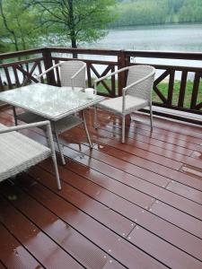 une table et des chaises sur une terrasse avec vue sur l'eau dans l'établissement Jezioro Marzeń na Kaszubach, à Stare Czaple