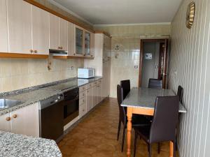 a kitchen with a table and chairs and a counter at Apartamento Naron in Narón