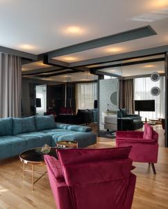 a living room with blue couches and red chairs at Hotel River Park in Cluj-Napoca