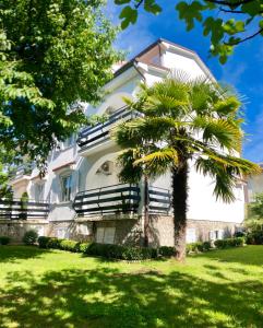 a white house with a palm tree in front of it at Apartments Bella Vita 1 in Malinska