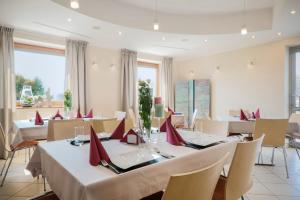 un restaurante con mesas blancas y sillas con servilletas rojas en Hotel Aviator en Kamień Śląski