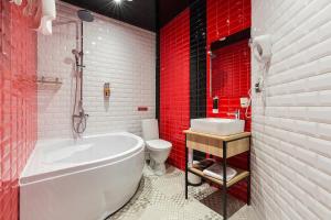 baño con bañera blanca y paredes rojas en Hotel Demut, en San Petersburgo