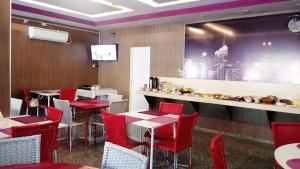 una sala da pranzo con sedie rosse e un bar di Itaverá Master Hotel a Presidente Prudente