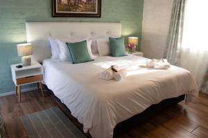 1 dormitorio con 1 cama blanca grande y toallas. en Parkside Guesthouse, en Ladismith