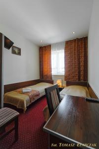 a hotel room with two beds and a table at Hotel Kaprys in Świdnik