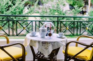 een tafel met 2 stoelen en een theeset op een balkon bij Skiron Studios in Kineta