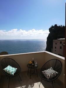 two chairs and a table on a balcony with the ocean at Alex Room in Manarola