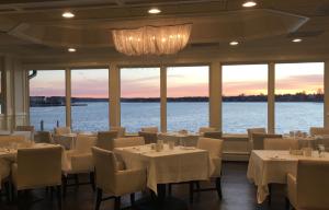 a restaurant with tables and chairs with a view of the water at Oyster Point Hotel in Red Bank