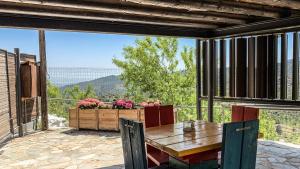 een houten tafel en stoelen op een patio met uitzicht bij Vasiliou House Krimenos in Khandria