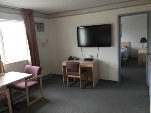 a hotel room with a television and a table and chairs at DC Lodge in Dawson Creek