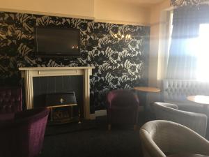 a waiting room with a fireplace and a tv and chairs at The Savoy in Skegness