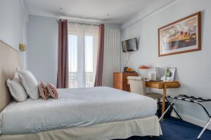 Schlafzimmer mit einem Bett, einem Schreibtisch und einem Fenster in der Unterkunft Hotel Le Berry in Saint-Nazaire