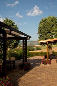 a patio with a wooden pergola and tables and flowers at Country House Binnella in Cingoli