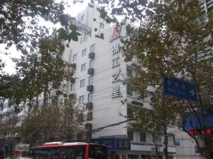 a white building with a red bus in front of it at Jinjiang Inn - Chengdu Jinxianqiao in Chengdu