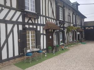 - un bâtiment noir et blanc avec des chaises et une table dans l'établissement Le Mouton Gras, à Aumale