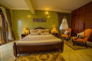 a bedroom with a large bed and two chairs at Greens Guest Homes in Mutungo