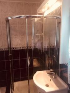 a bathroom with a sink and a shower at Maisie's Seaside Cottage in Quilty