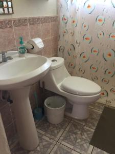 een badkamer met een wastafel, een toilet en een douchegordijn bij Shalpa surf villa in La Libertad