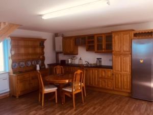 a kitchen with a table and a stainless steel refrigerator at Teach Beag Cois Tra in Miltown Malbay