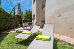dos sillas blancas y un paraguas en el césped en Residencial Llenaire Apartment, en Puerto Pollensa