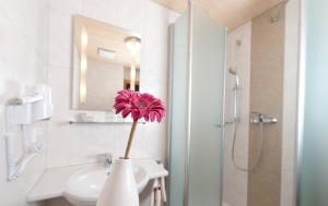 a pink flower in a white vase in a bathroom at Frankenhof in Scharnitz +75 photos