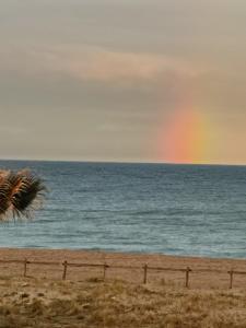 a rainbow over the ocean with a beach at Hotel de la Plage - Barcares in Le Barcarès