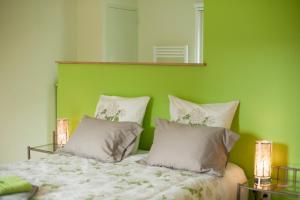 Dormitorio verde con cama con sábanas y almohadas blancas en Moulin de Gaubourg en Saint-Mélaine-sur-Aubance
