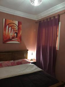 1 dormitorio con cama y cortina púrpura en Wiss Appartement, en Essaouira