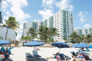 a group of people sitting on a beach with blue umbrellas at Miami Hollywood High Rise Condo 004-22bvic in Hollywood