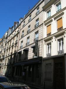 Un grand bâtiment blanc avec des fenêtres donne sur une rue. dans l'établissement Hotel Darcet, à Paris