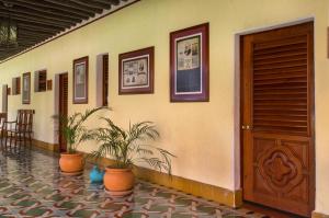 a hallway with potted plants and a wooden door at Hacienda Uxmal Plantation & Museum in Uxmal