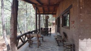 une terrasse couverte d'une maison avec des chaises et des tables dans l'établissement Cabañas Tapalpa Sierra del Tecuan, Cabaña Venado, à Tapalpa