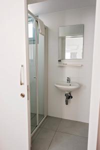 uma casa de banho branca com um lavatório e um espelho em Pyramos Hotel em Pafos