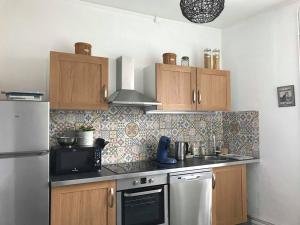een keuken met een koelkast en een fornuis top oven bij Le Compostelle Chic, Charme, Confort, Cocooning 80 m² in Saint-Léonard-de-Noblat