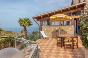 a house with a table and an umbrella on a patio at Villa Azzurra con vista sul mare in San Vito lo Capo