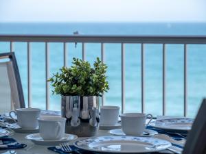 a table with plates and cups and a vase with flowers at SPECTACULAR SEA VIEW Fuengirola in Fuengirola