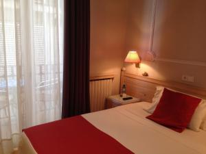 a bedroom with a bed with a red pillow and a window at Hotel Celimar in Sitges