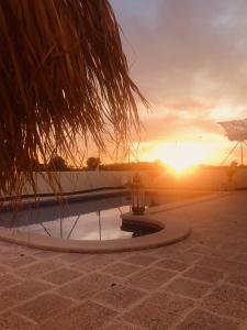 a sunset over a swimming pool with the sun setting at Rancho de Sueños in La Zarza