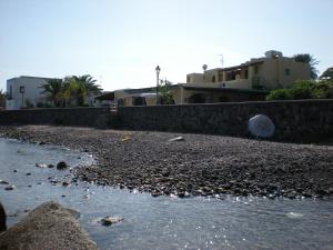 una playa rocosa con edificios en el fondo en Il Delfino en Santa Marina Salina