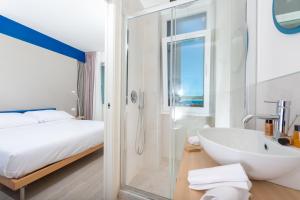 een badkamer met een bad, een wastafel en een bed bij L'Alba Hotel in Marina di Pietrasanta