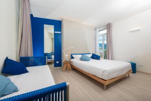 2 letti in una camera con blu e bianco di L'Alba Hotel a Marina di Pietrasanta