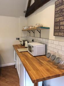 y cocina con microondas y encimera de madera. en The Stables At Harby en Melton Mowbray