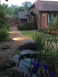 a garden with a pond in front of a house at The Stables At Harby in Melton Mowbray