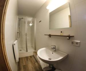 ein Bad mit einem Waschbecken und einer Dusche mit einem Spiegel in der Unterkunft LOOK Hotel & Rooms in Crailsheim